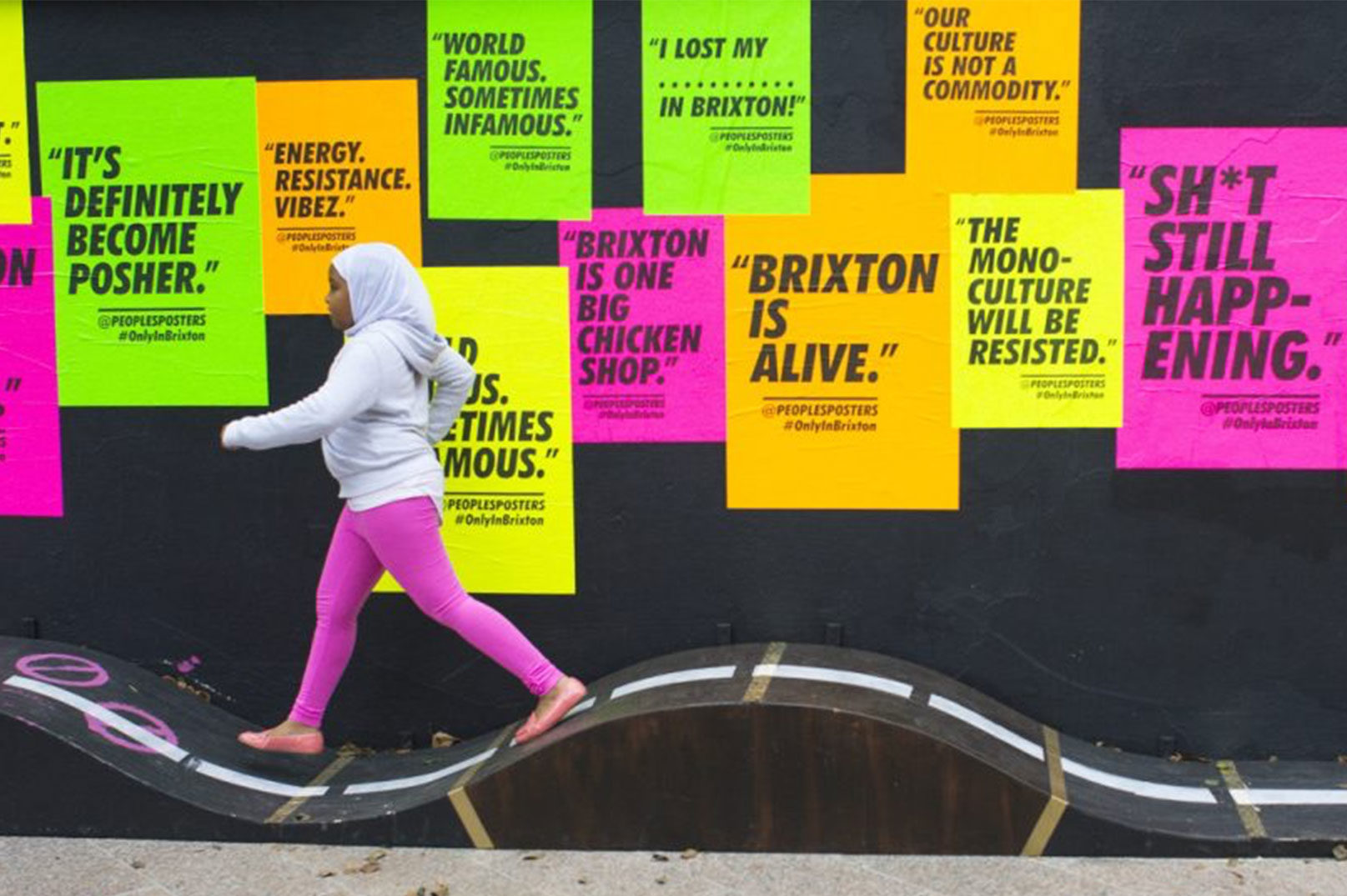 Girl walking past positive feedback posters in Brixton