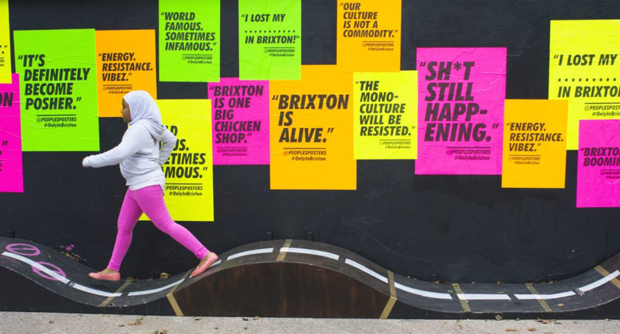 Girl walking past positive feedback posters in Brixton