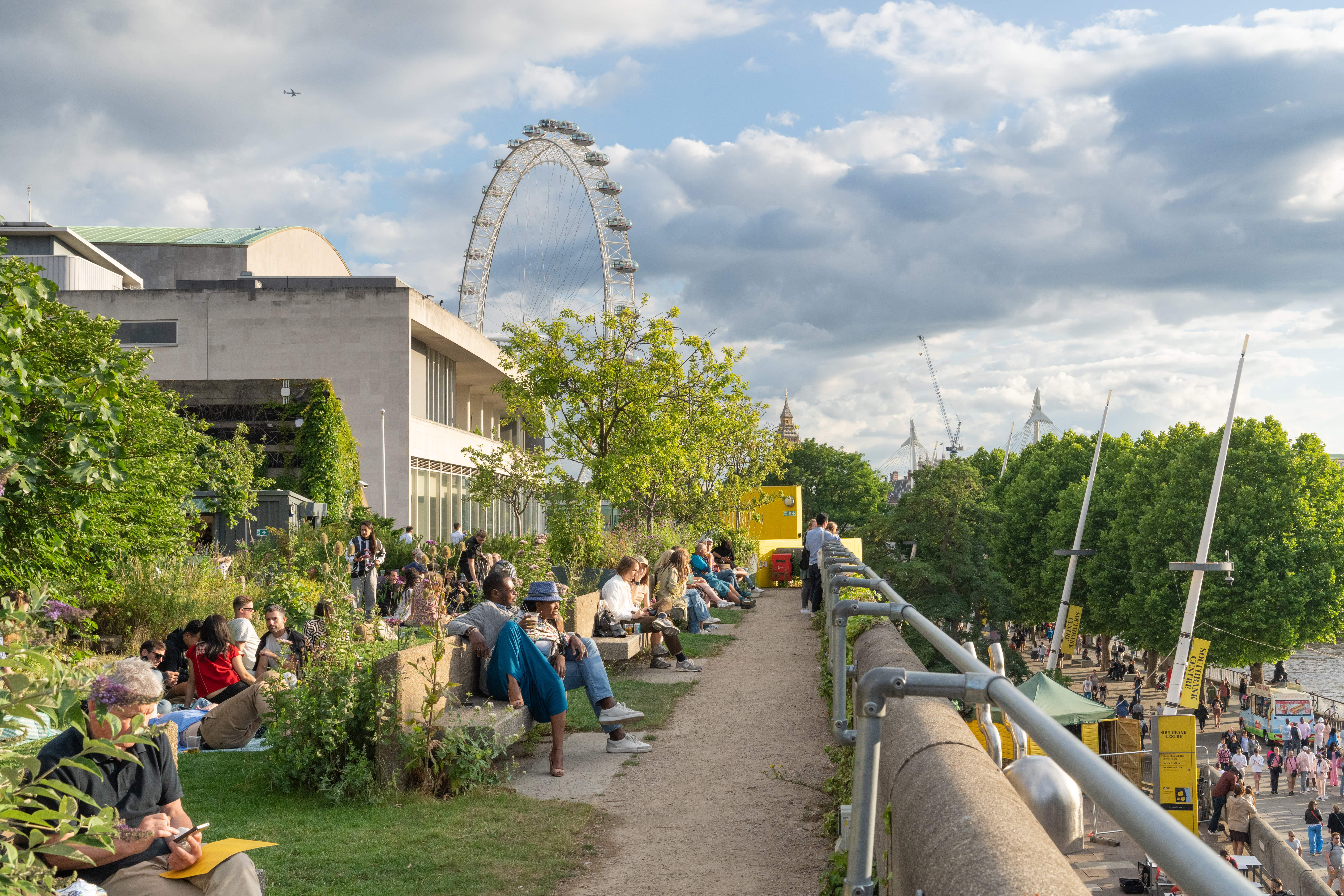 A view of the Southbank centre and London Eye with people sat outside.