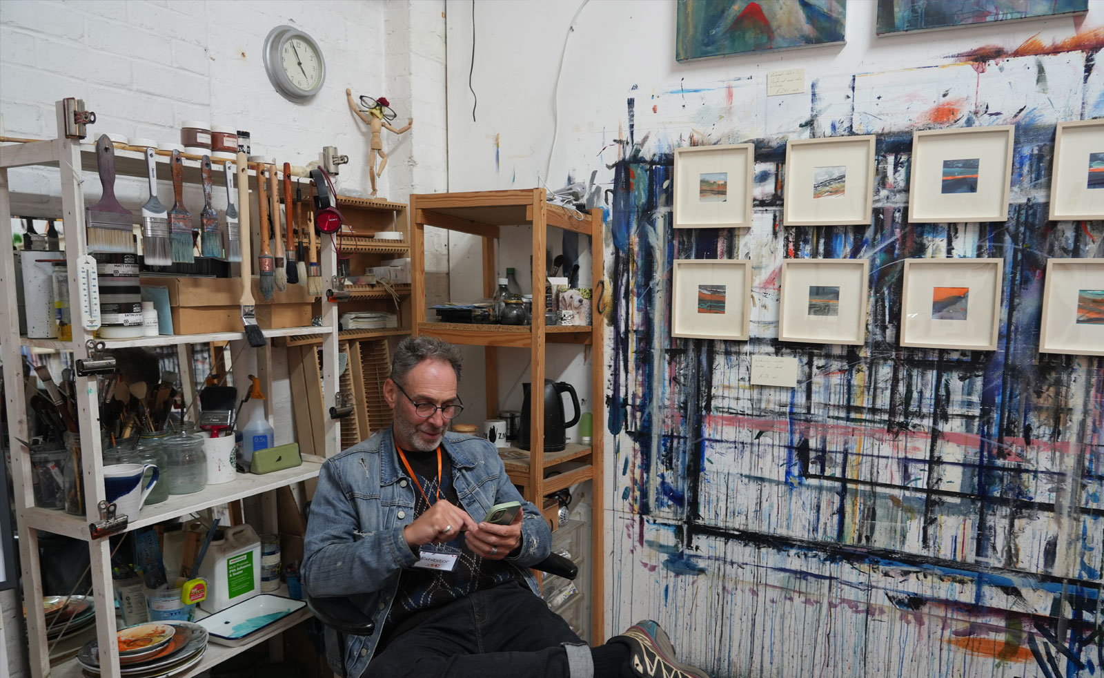 a male artist sits in his studio with artwork and materials