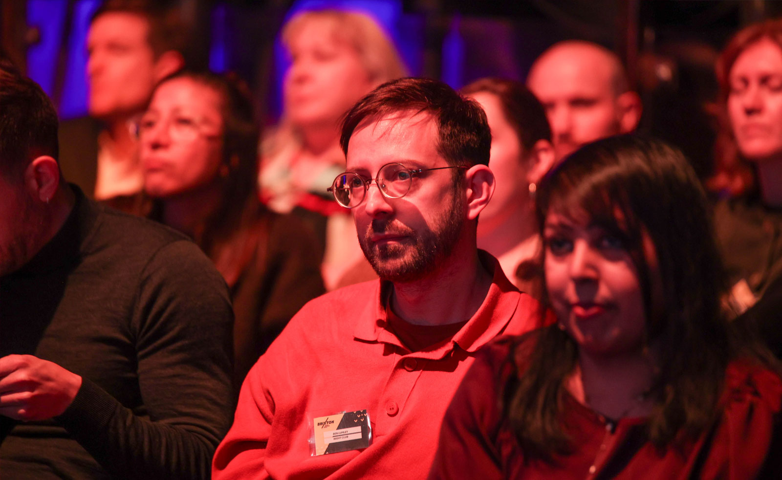 Seated audience members lit by stage lights
