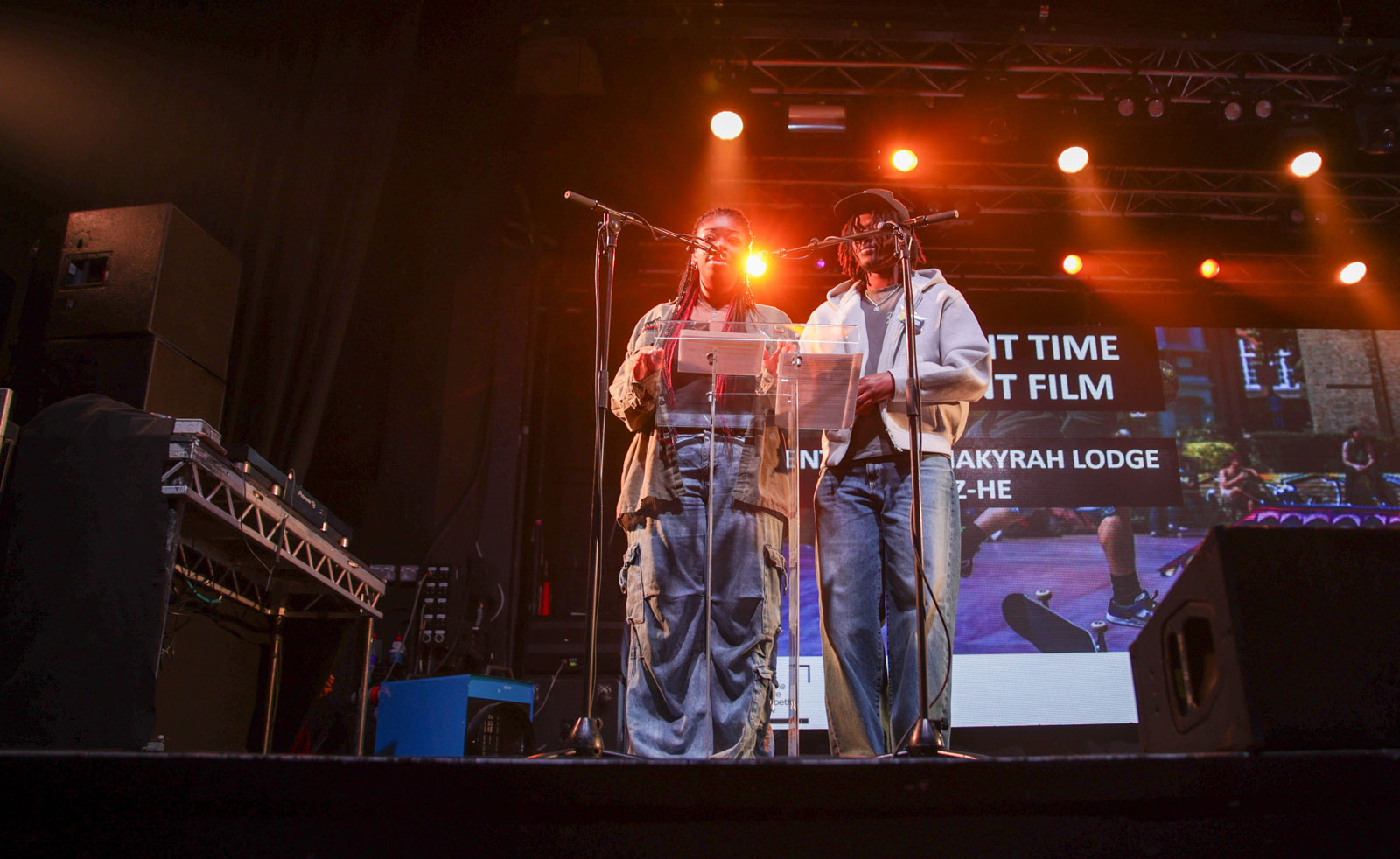Two young people speaking at a lectern on stage