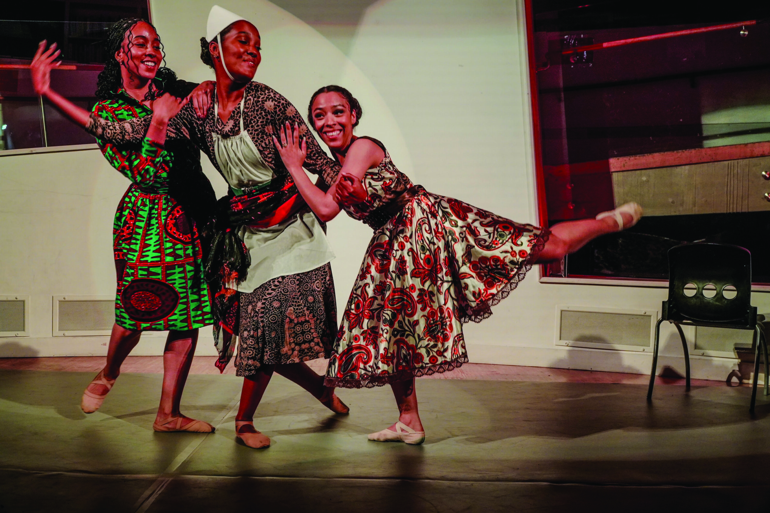 A group of three dancers in Afro-Caribbean inspired dresses, performing in Black British Ballet at Clapham Library