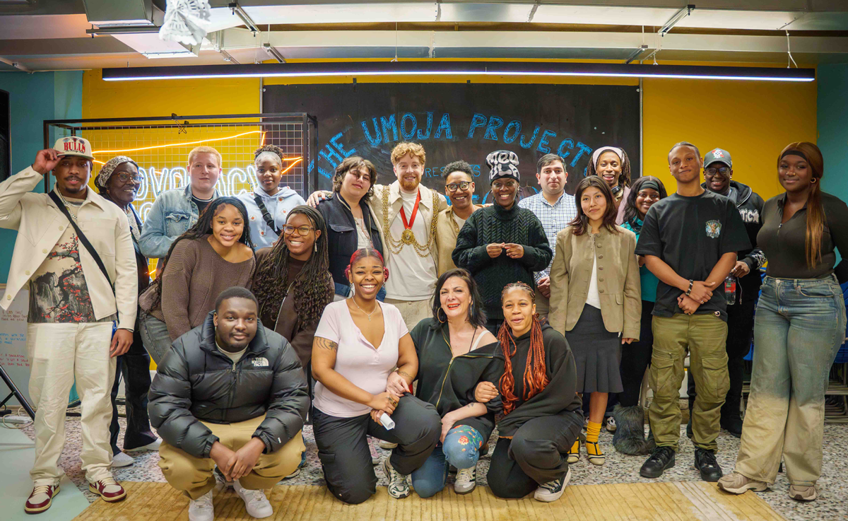 A group photo featuring about twenty young people of diverse backgrounds inside a community space