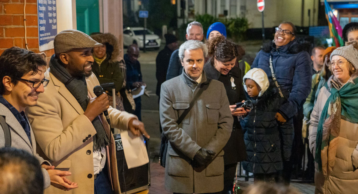 A group of Lambeth Councillors and officials from the Portuguese Embassy speaking to an audience of people standing outside at night