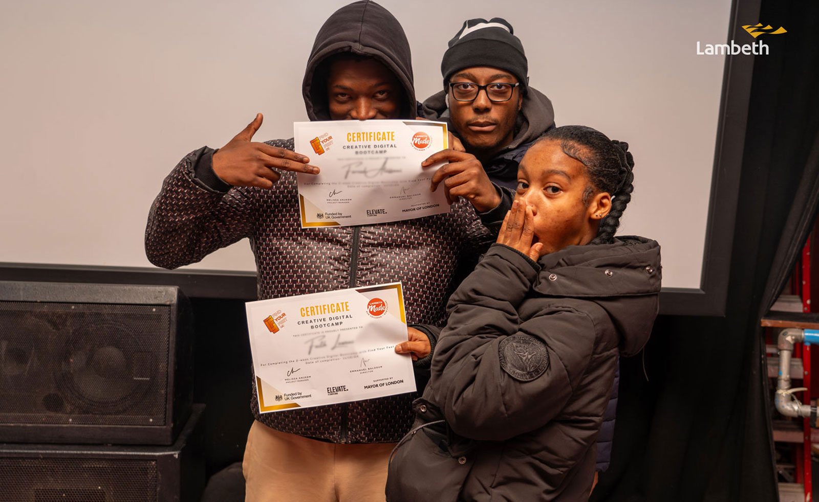 Three young people posing with certificates at celebration event