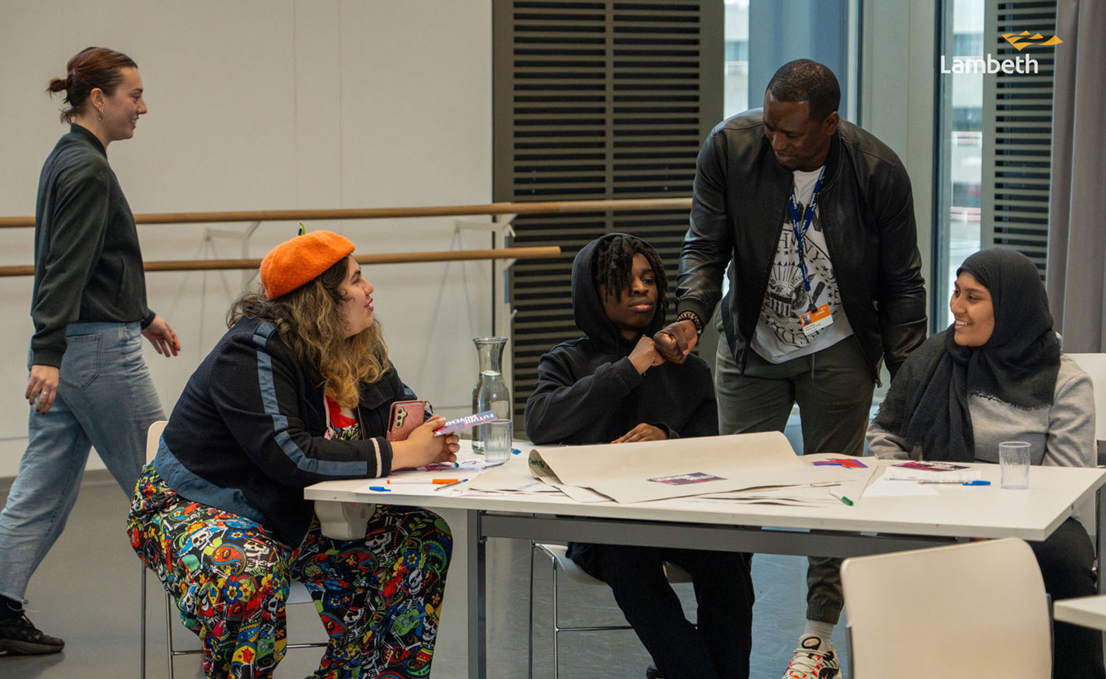 Young people sitting around a table intearacting with facilitator.