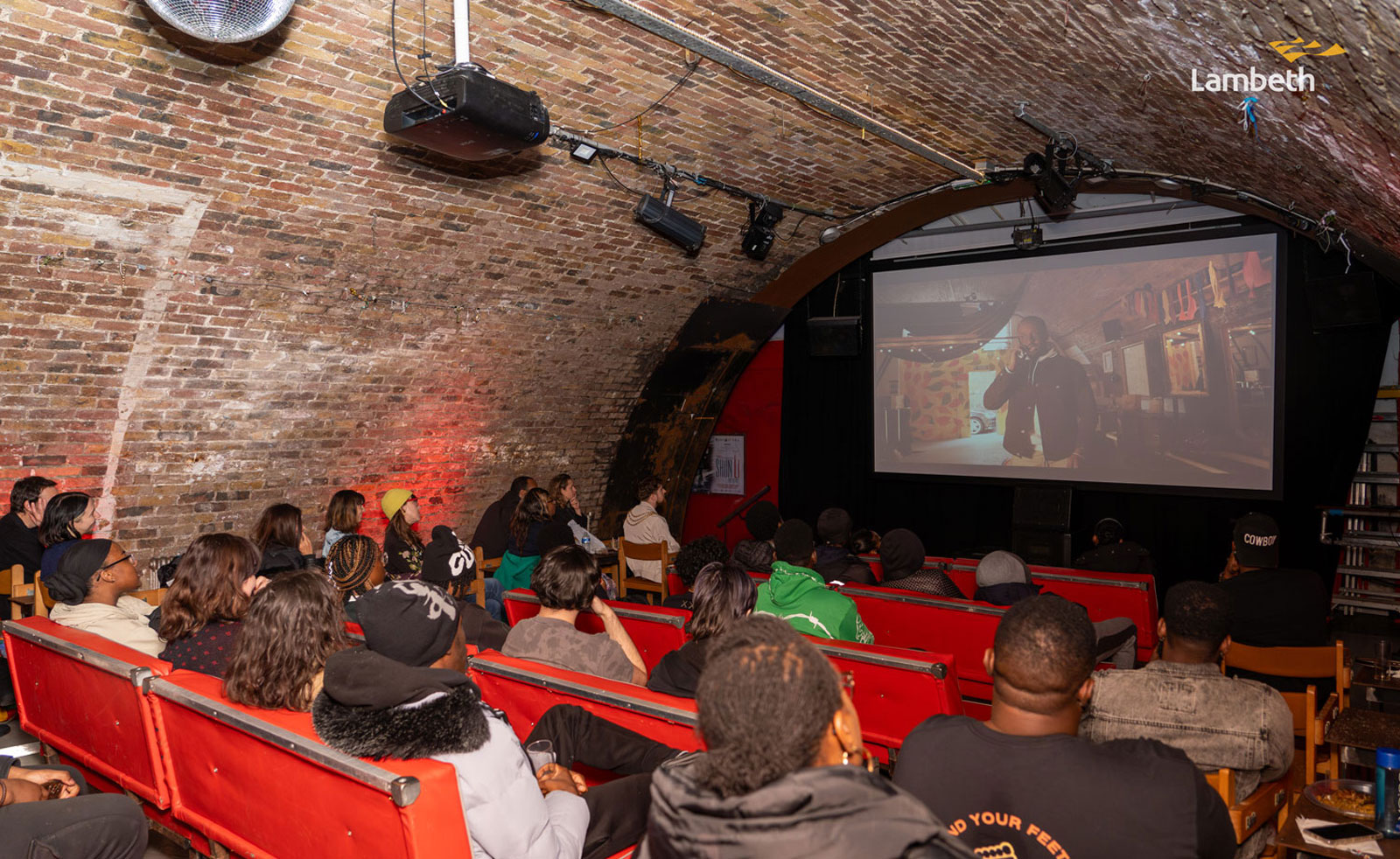 People at the end of programme celebration event watching the work created by young people.