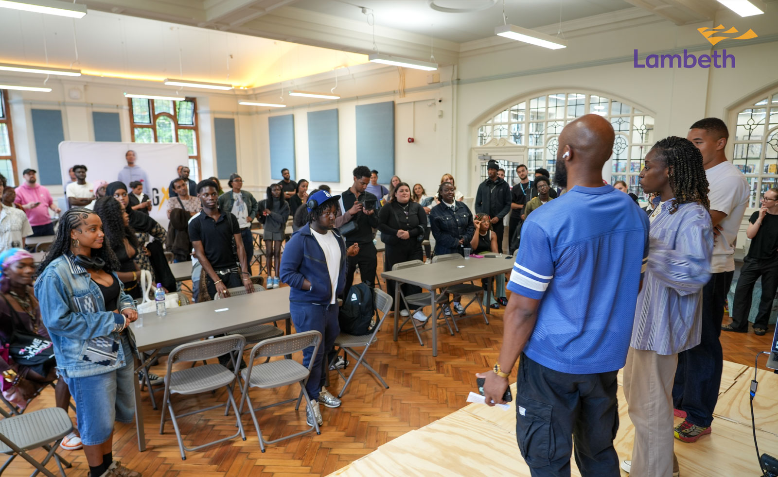 A picture of a person on stage in front of a group of people looking at them