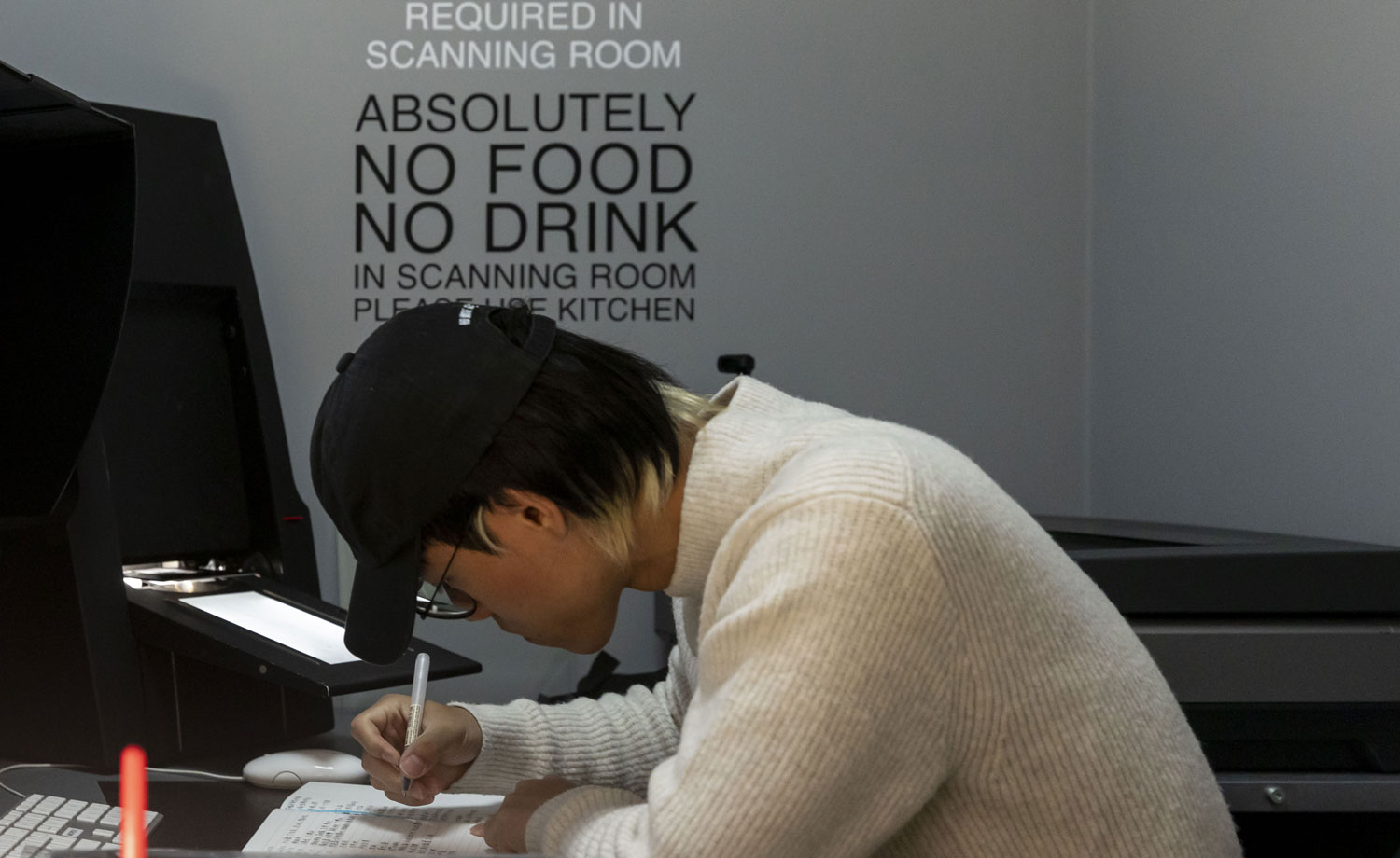 Man in black cap writing in notepad