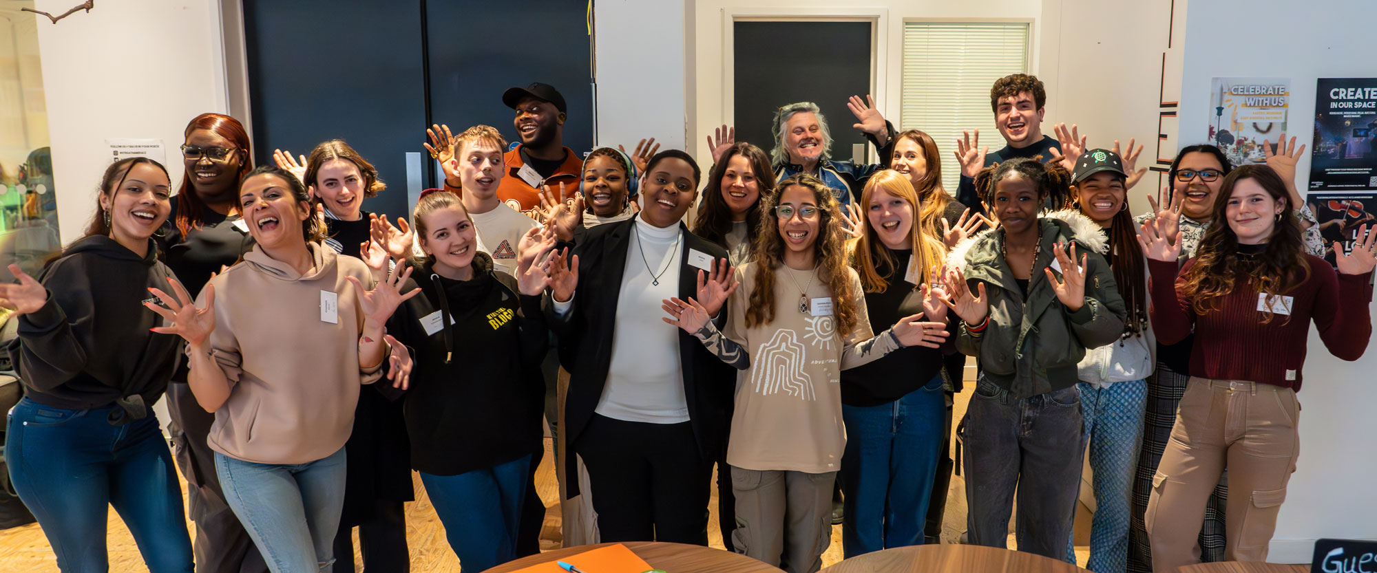 A group of young people and facilitators pose smiling for the camera