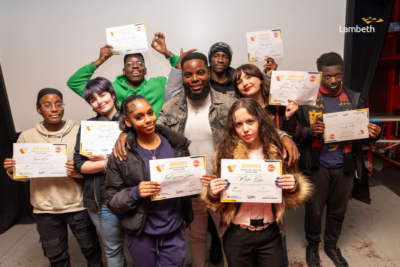 Group of young people and their mentor posing with their certificates after a successful creative bootcamp