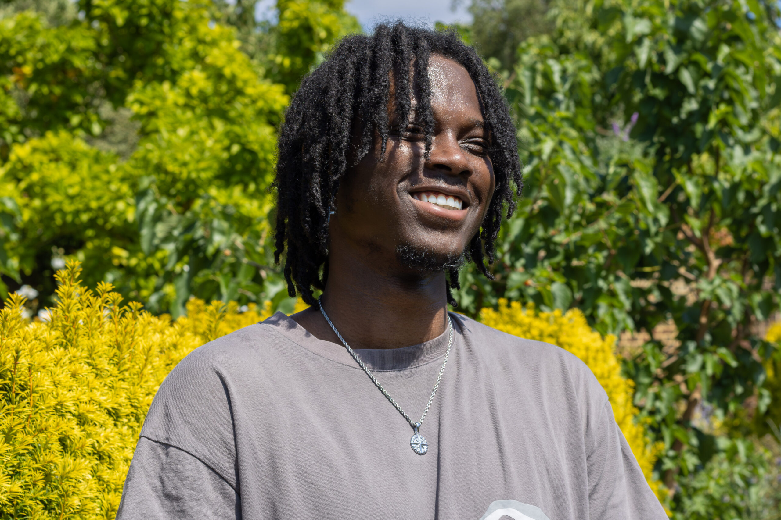 Elevator wearing a grey t-shirt smiling in front of trees