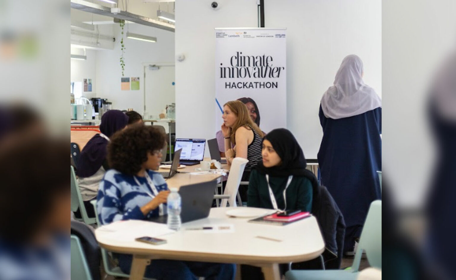 Participants of the Climate Innovather programme sit on tables in groups as part of a workshop.