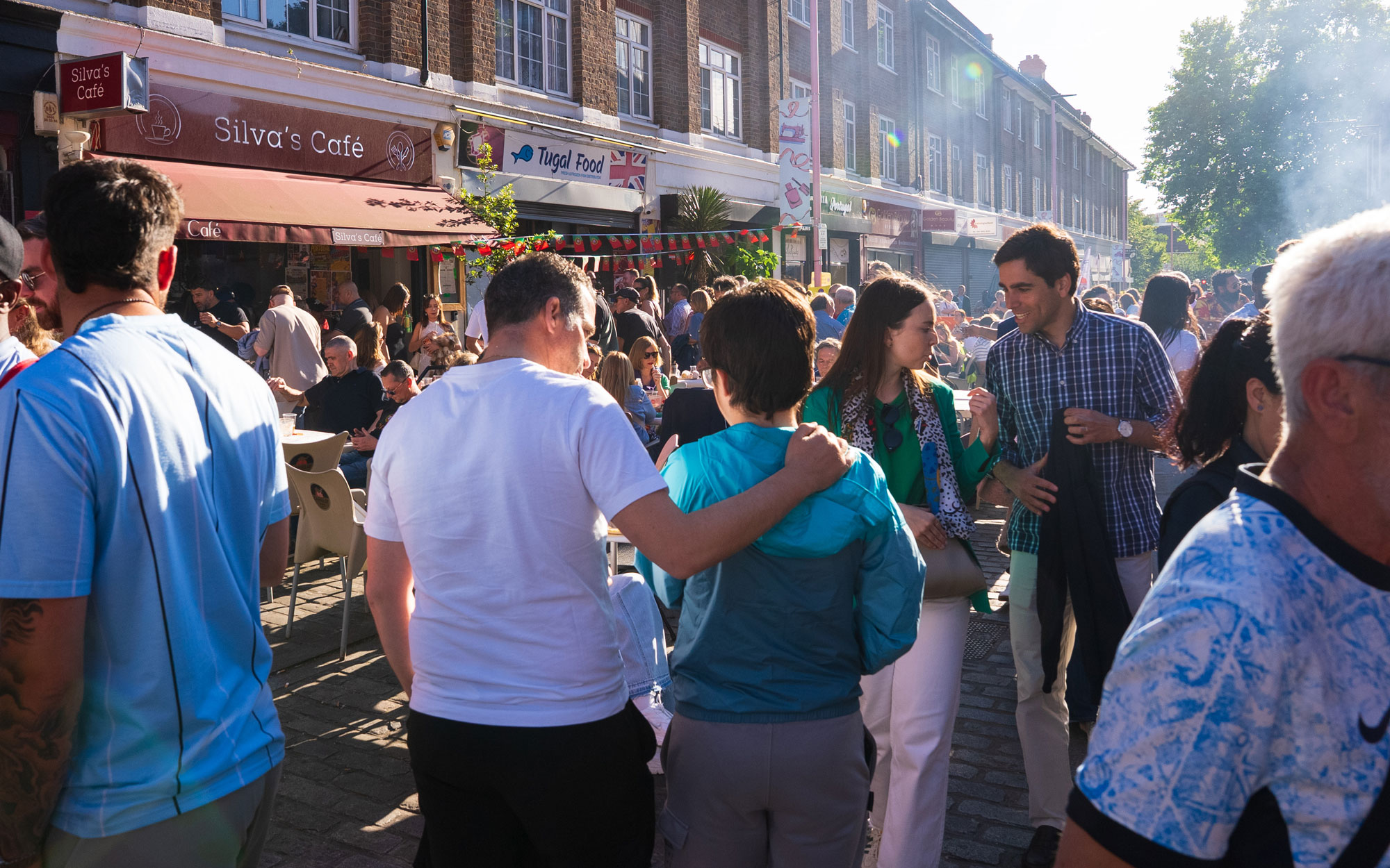 Crowds gather along a pedestrianised street in Little Portugal, enjoying outdoor dining and the Day of Portugal celebration in Lambeth.