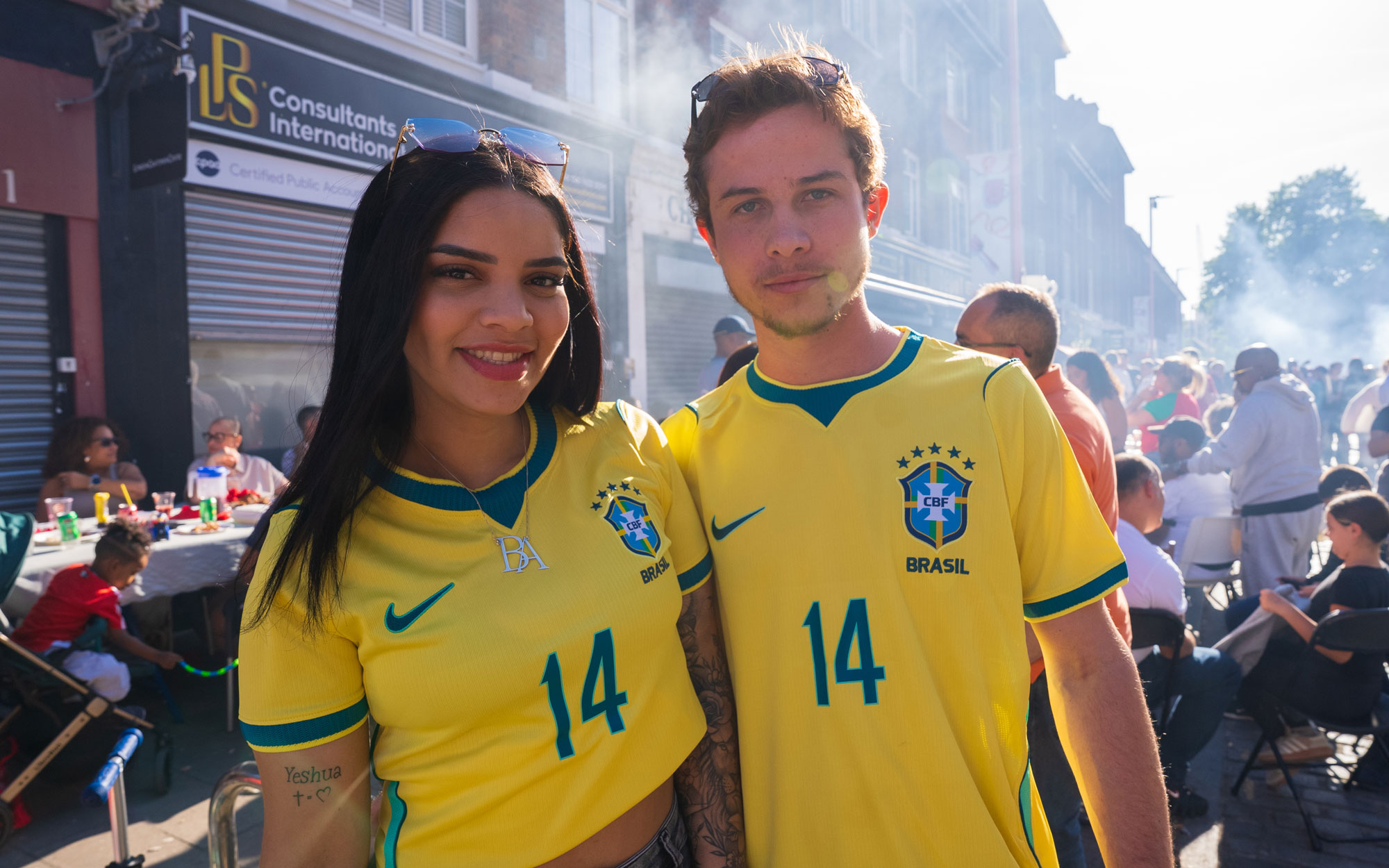 Two festival-goers wearing Brazil football shirts pose together at the Day of Portugal celebration.