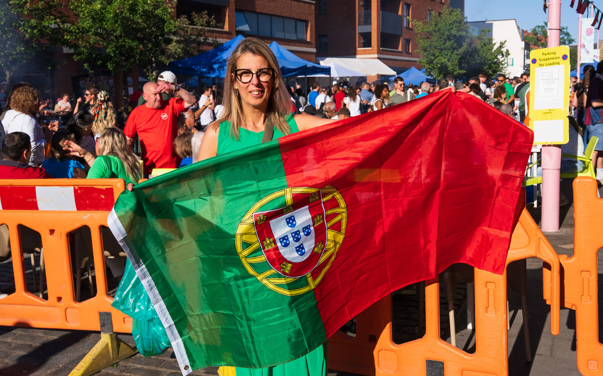 Festival attendee holding a large Portuguese flag while standing among the crowd.