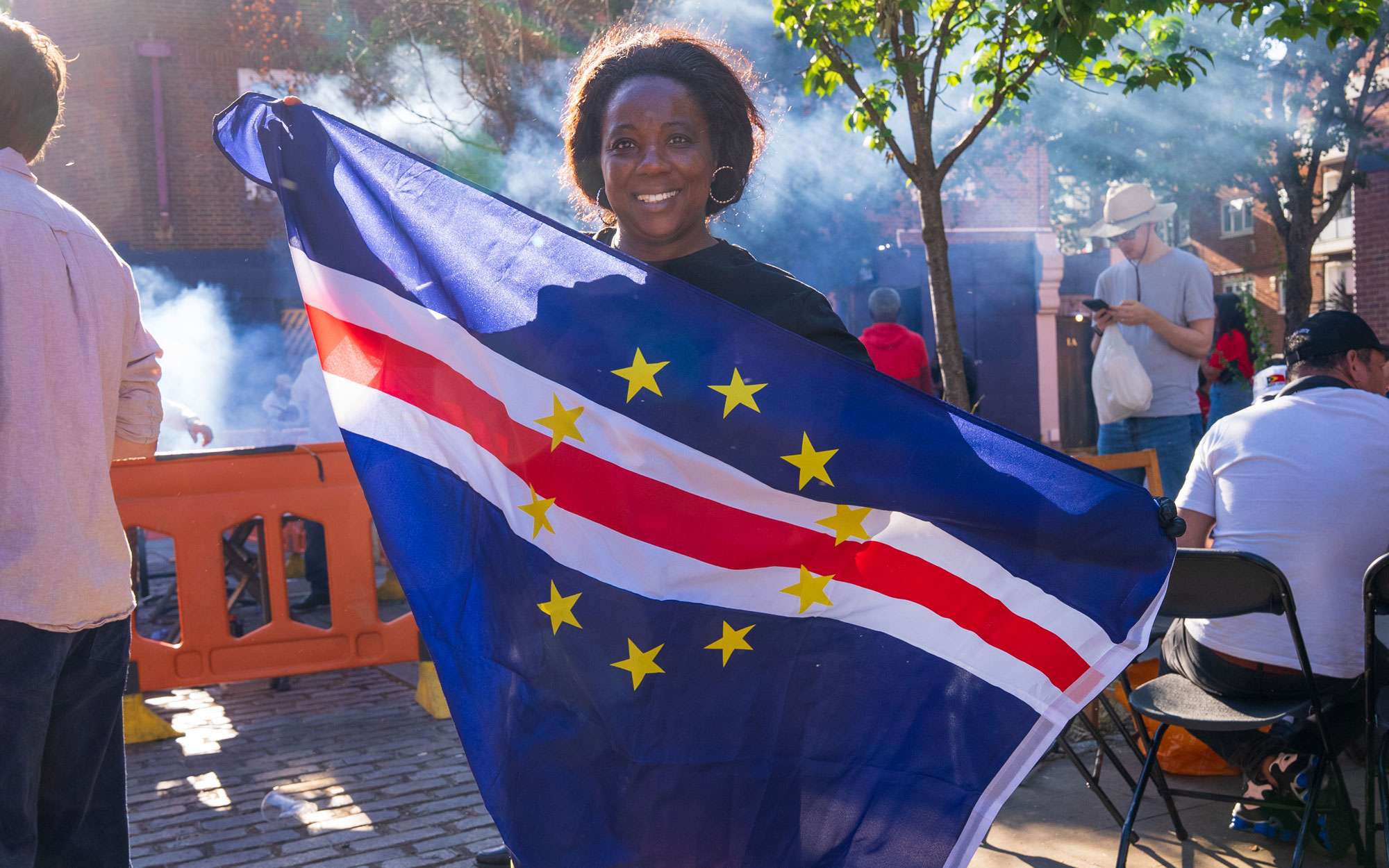 Festival attendee smiling while holding the national flag of Cape Verde.