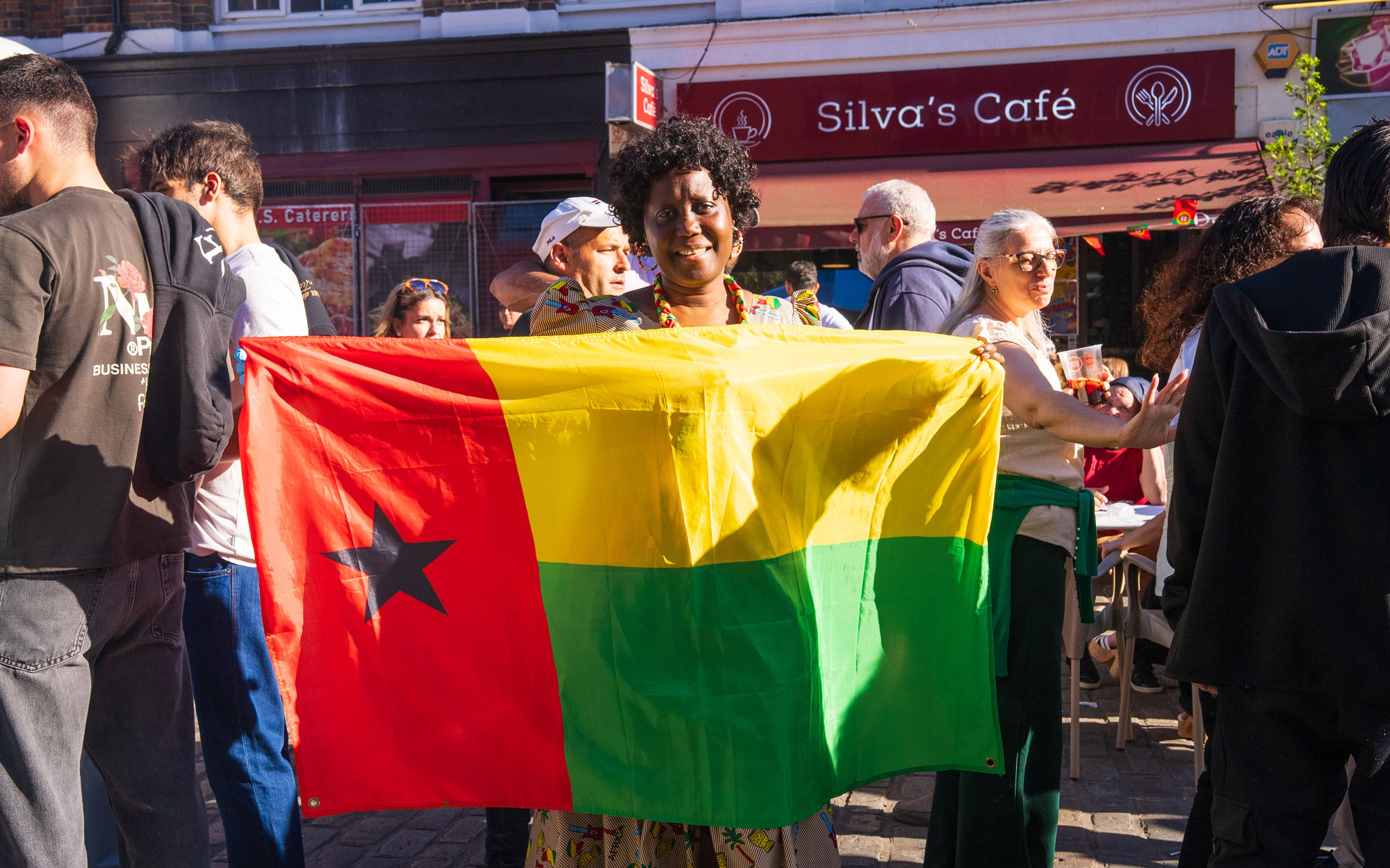 Festival attendee holding the national flag of Guinea-Bissau during the multicultural celebration.