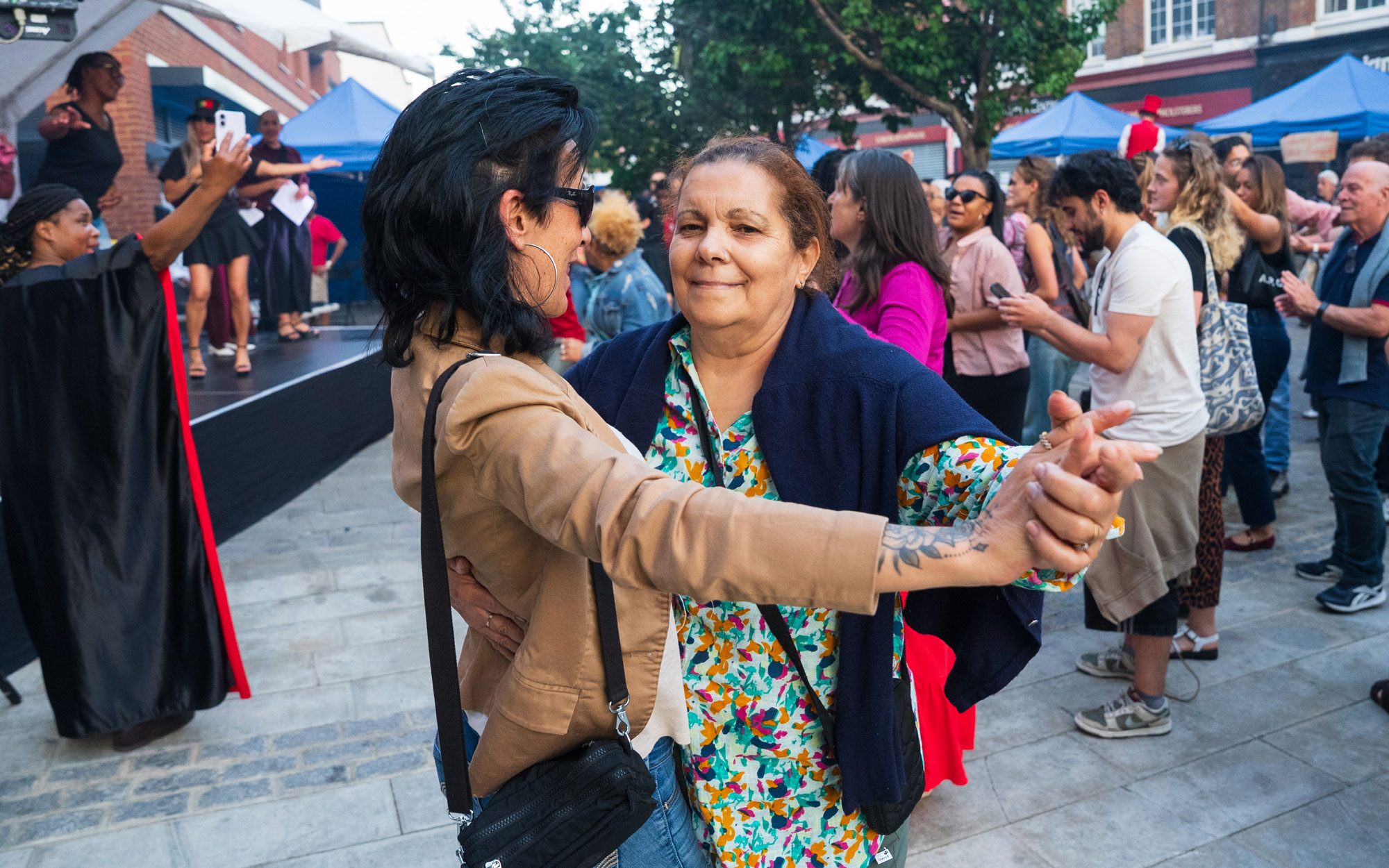 Two people dancing together in front of a stage as festival-goers gather for live entertainment.