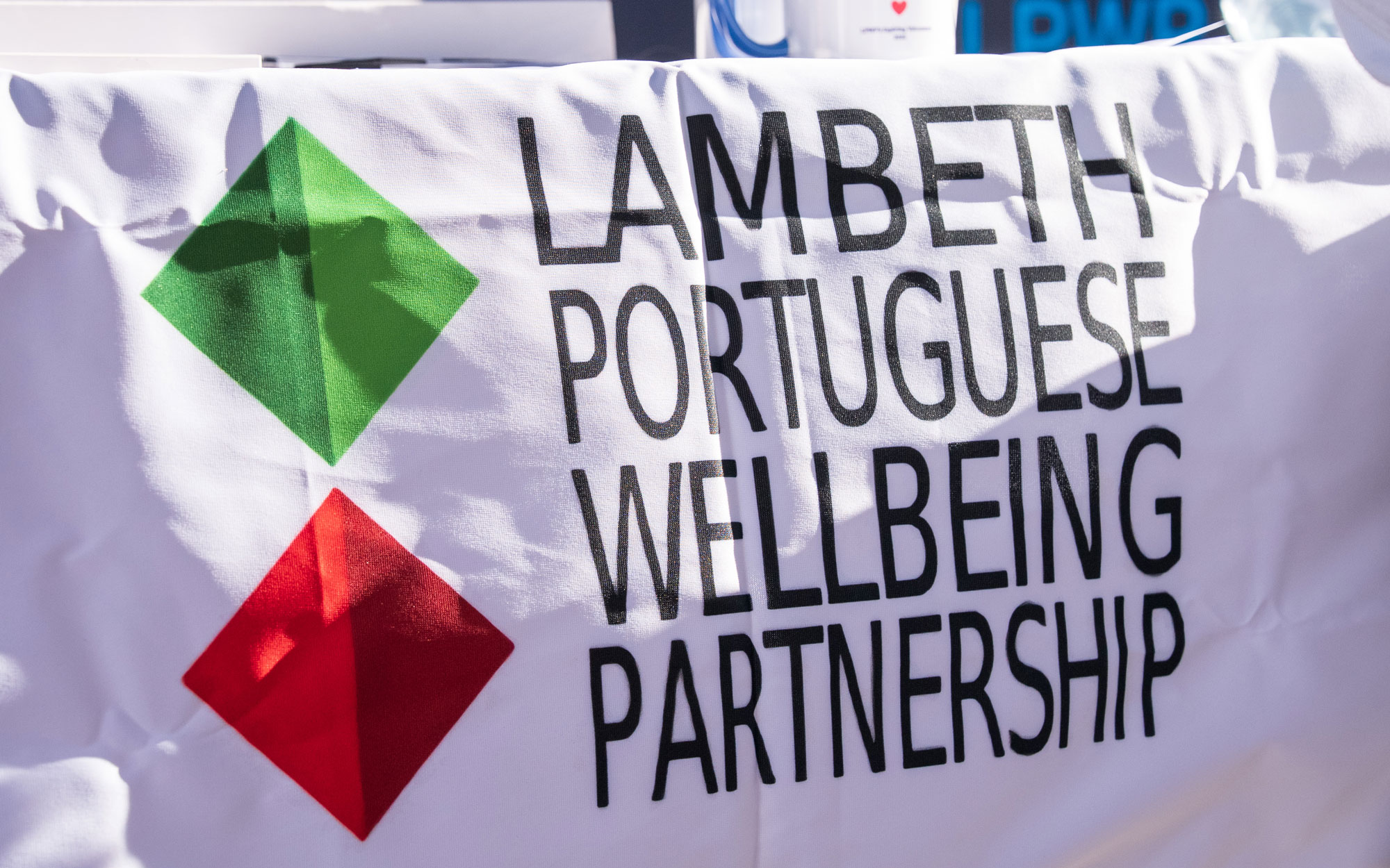 Banner for the Lambeth Portuguese Wellbeing Partnership displayed at an information stall.