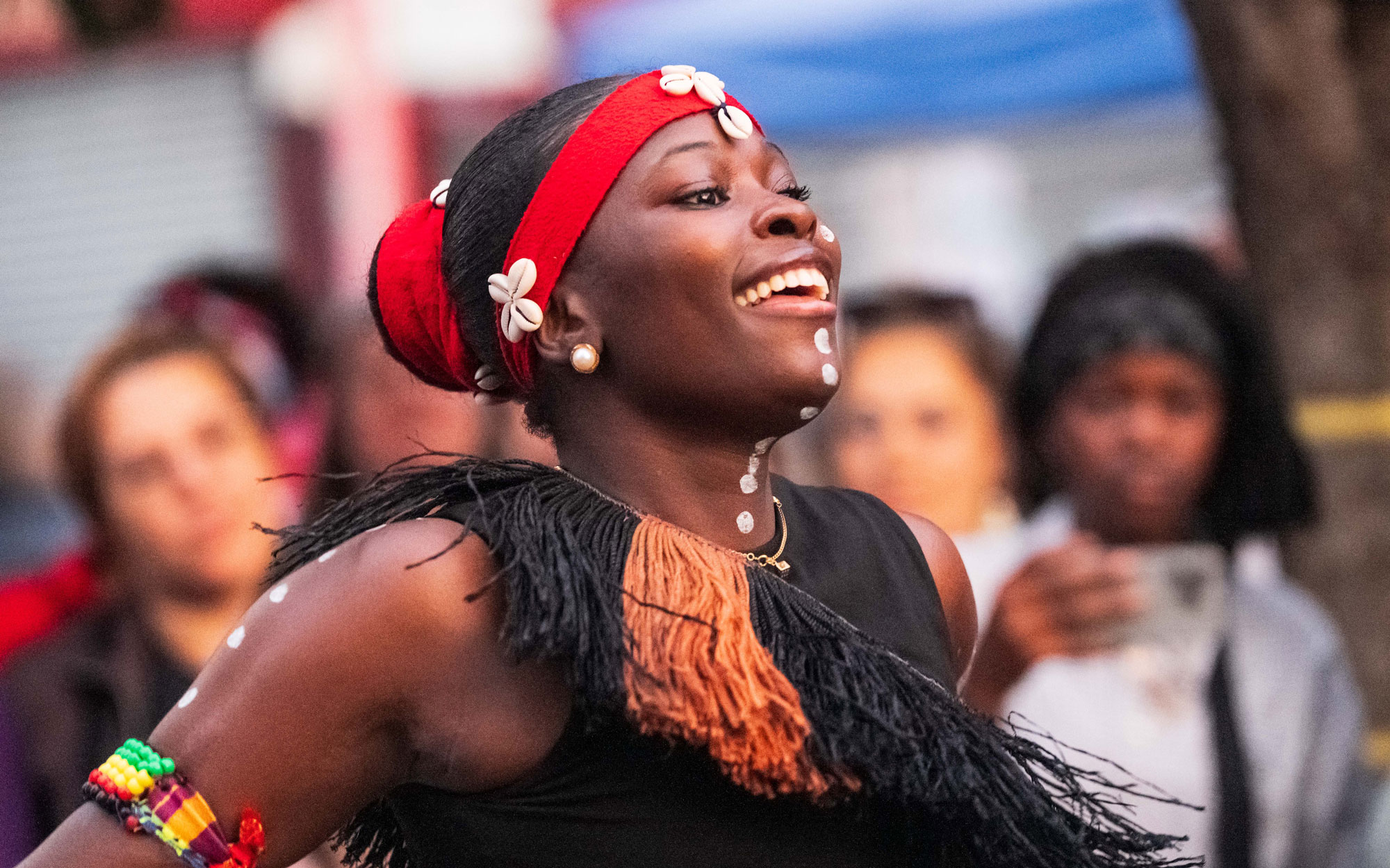 A smiling performer in traditional dress takes part in a cultural dance performance during the Day of Portugal celebration.