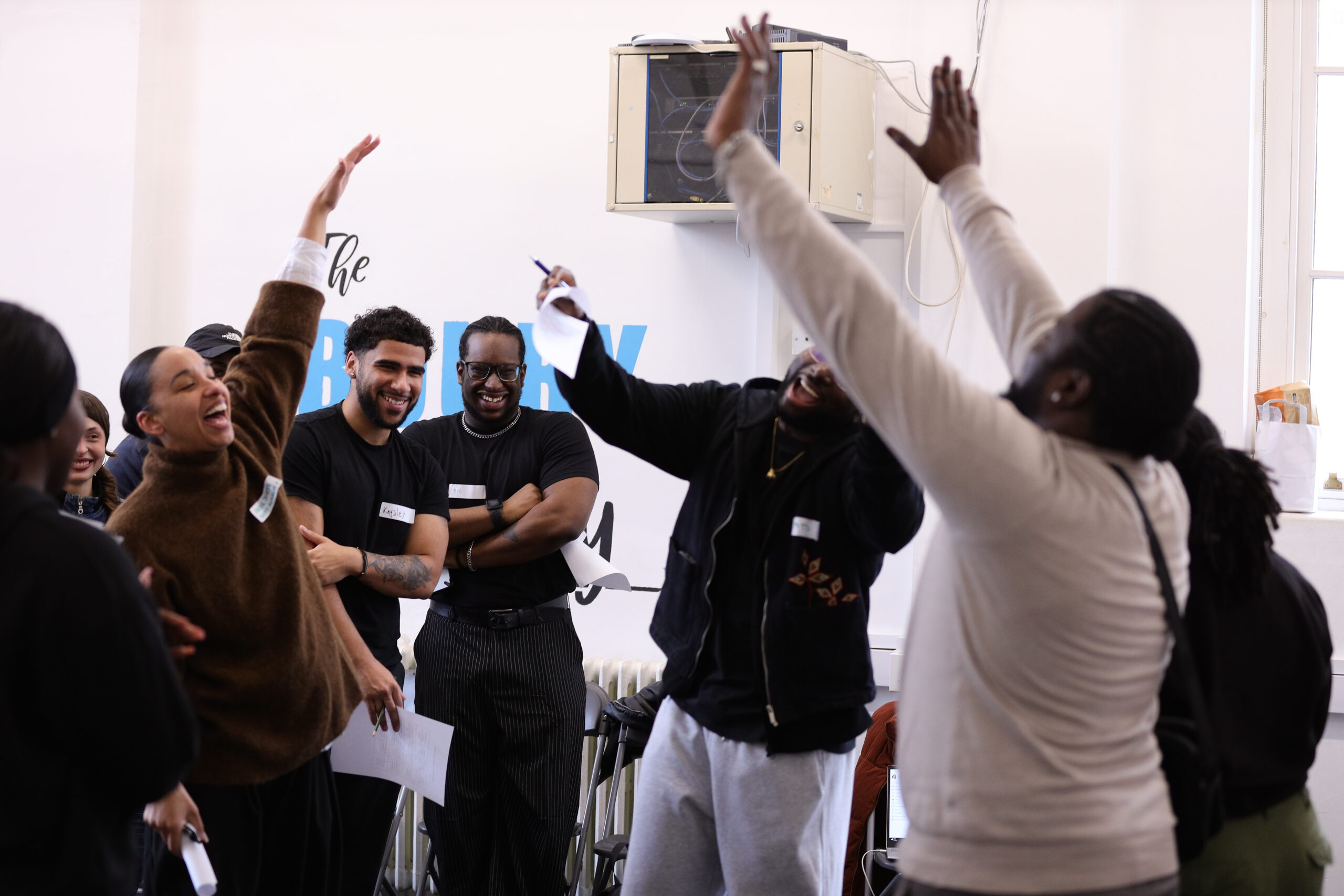 Young participants raise their hands and celebrate during an interactive group session.