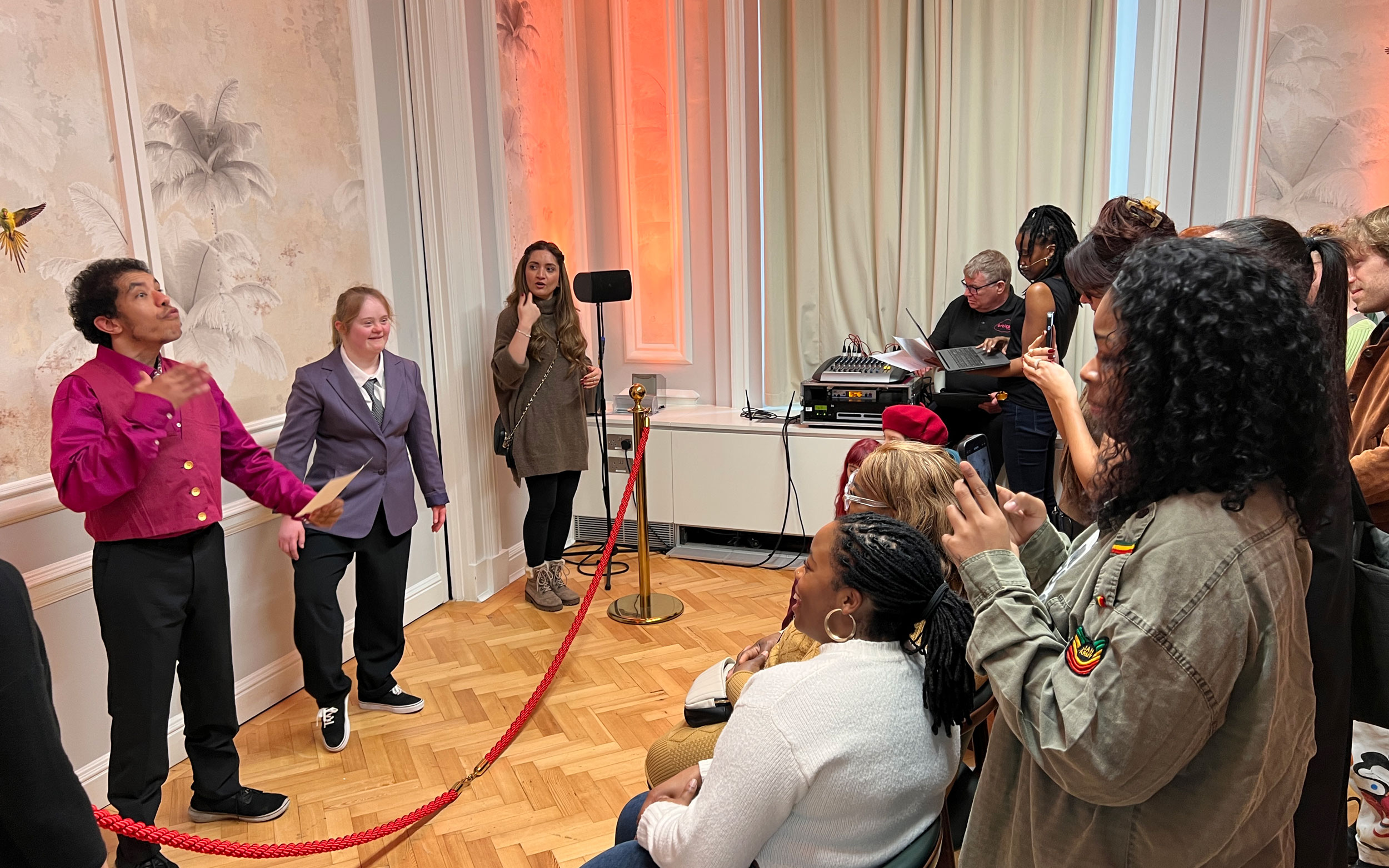 Performers address an audience gathered inside Lambeth Town Hall during a Danceology event, while attendees watch and take photos.