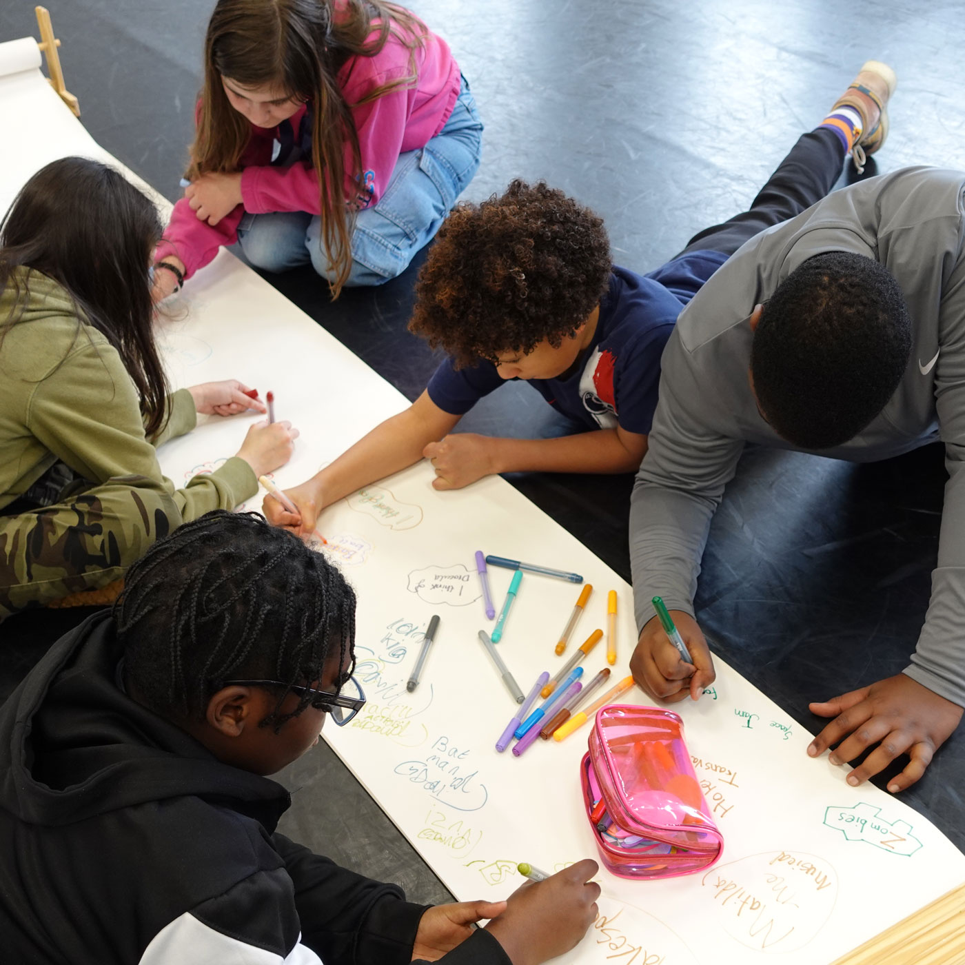 Young people work together on a large collaborative drawing during a creative workshop.