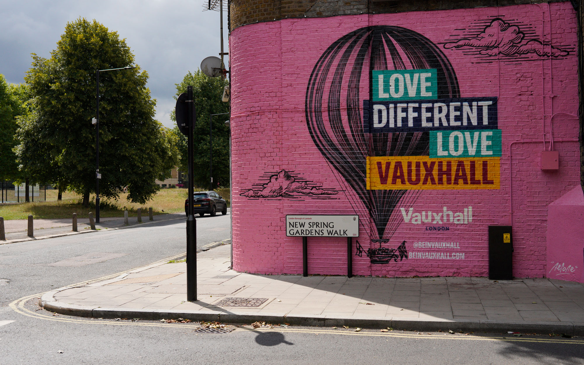 Large pink mural on the side of a building in Vauxhall featuring a hot air balloon and the words "Love Different Love Vauxhall
