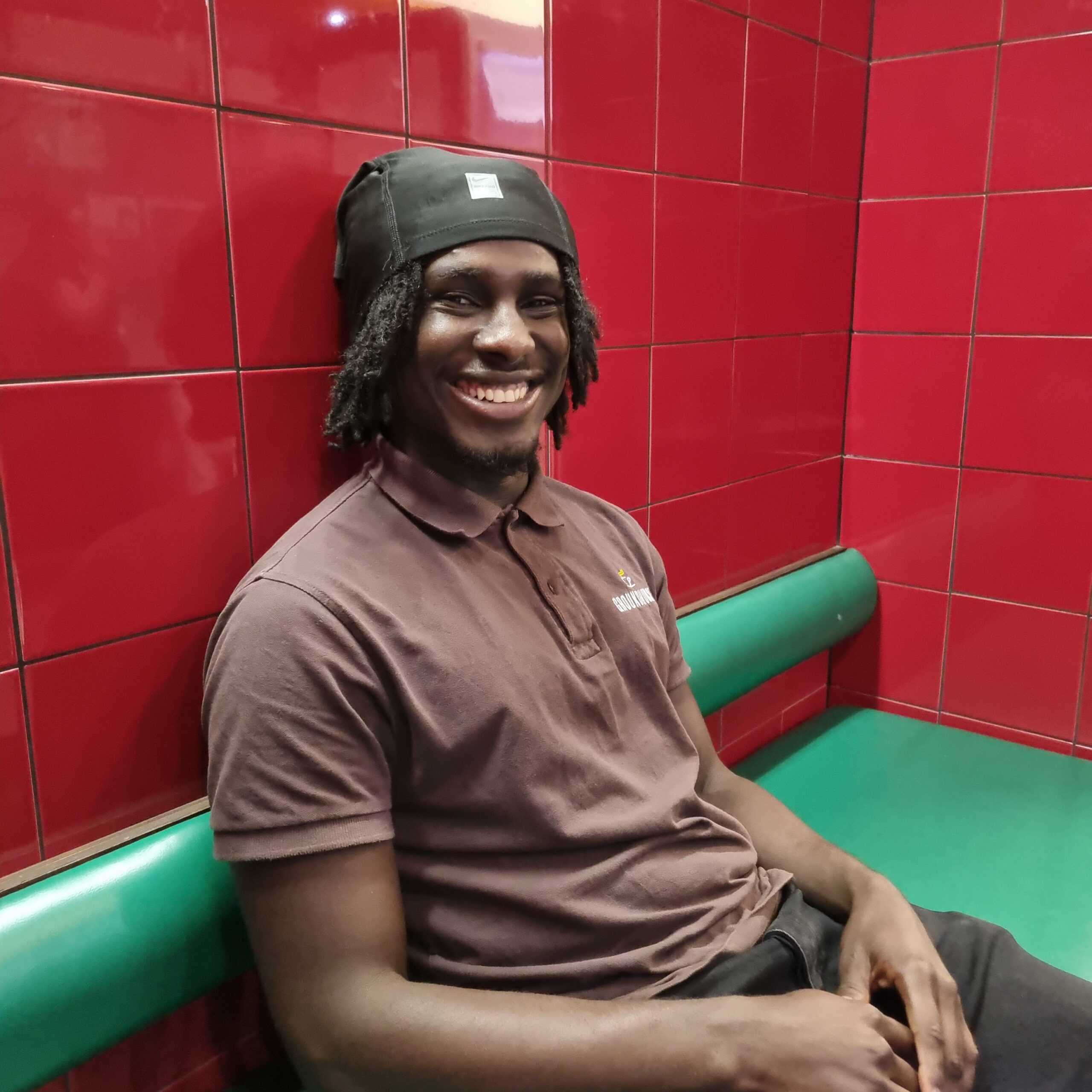 Mustafa, a young person, smiles at the camera whilst in uniform