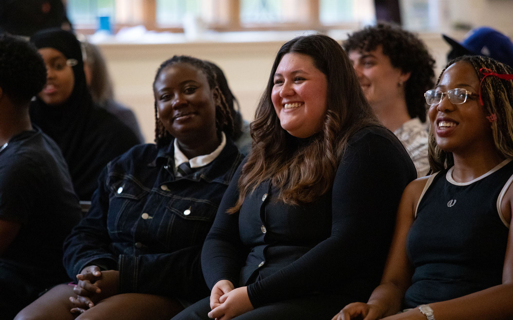 Young people smile and react while watching a presentation at a Trash Gxng event.