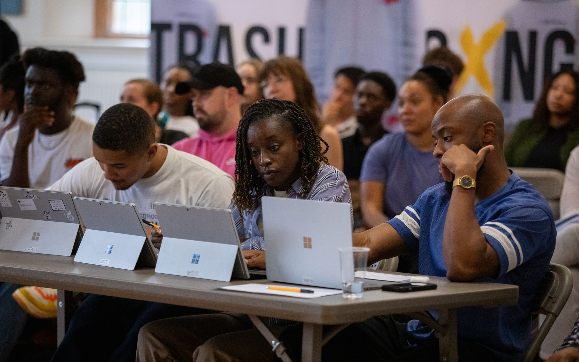 Three panellists sit behind laptops listening to presentations at a Trash Gxng creative bootcamp.