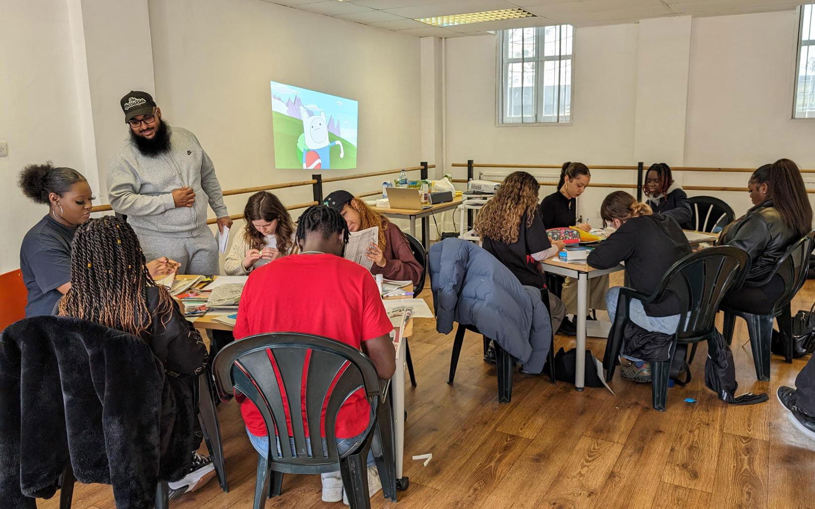 Young people work together on creative activities around tables during a workshop.